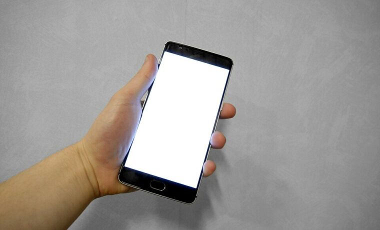 Dłonie trzymające smartfon z pustym ekranem, fotografia z 2016 roku. Ilustracja korzystania z telefonu, bez prezentacji konkretnego fałszywego wpisu.