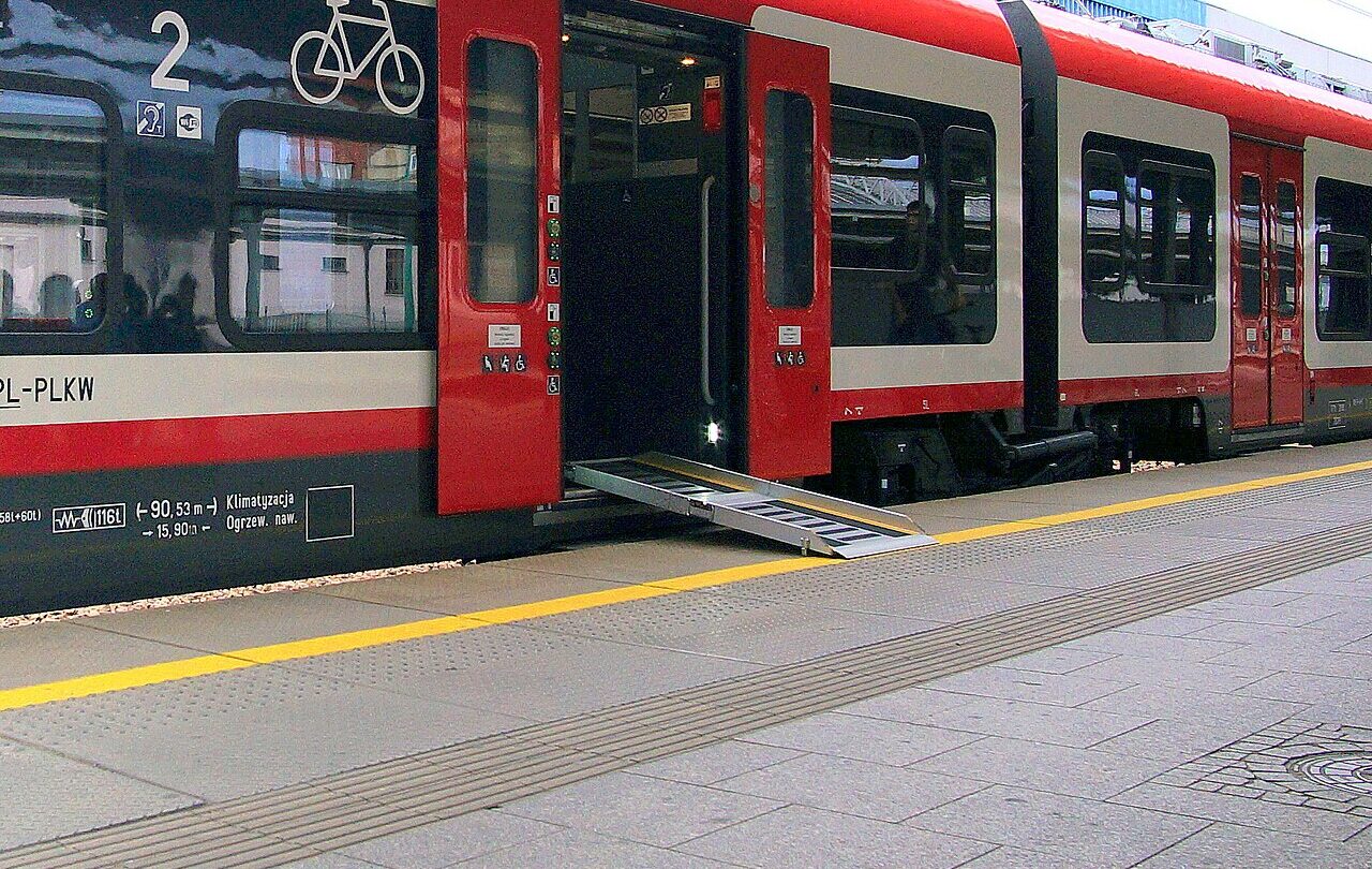 Rozłożona pochylnia umożliwiająca wjazd wózka do pociągu; fotografia ilustracyjna dostępności transportu