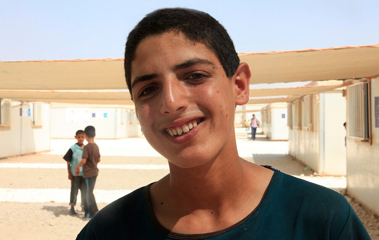 Młody edukator na terenie szkoły w obozie Zaatari w Jordanii, fotografia z 2013 roku; nie przedstawia wizyty UNICEF z 2026 ani osób opisanych w danych o ubóstwie