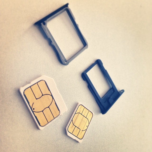 Karty micro-SIM i nano-SIM wraz z tackami telefonów; ilustracja usług komórkowych